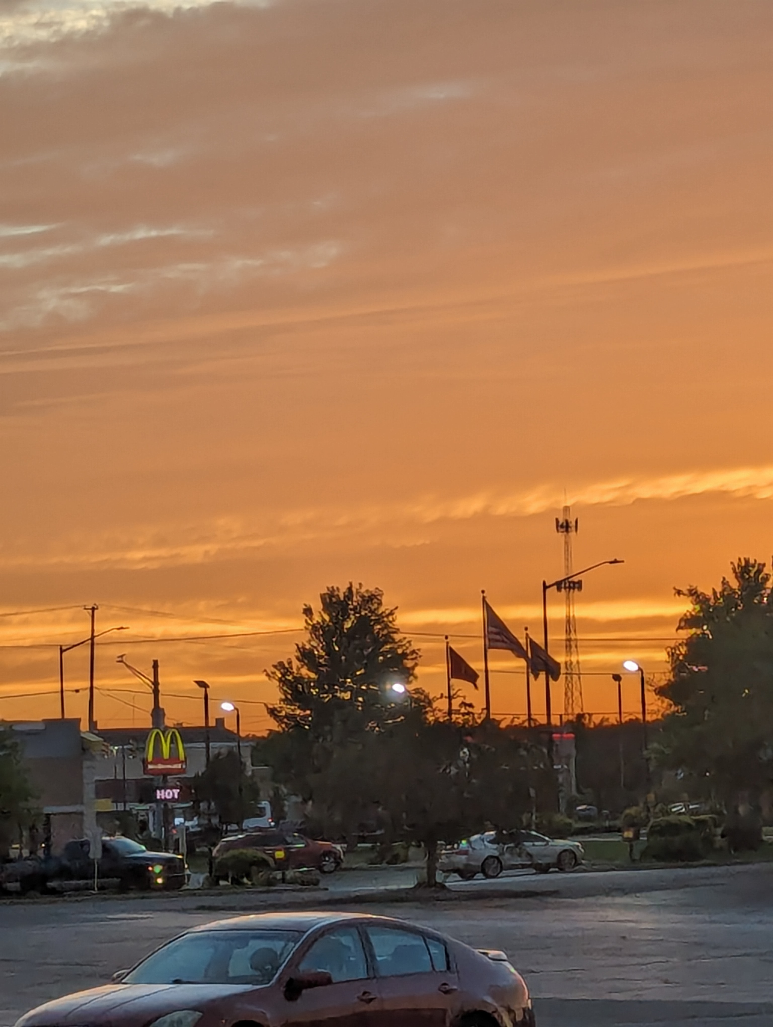 An orange evening sky glows over a commercial street.