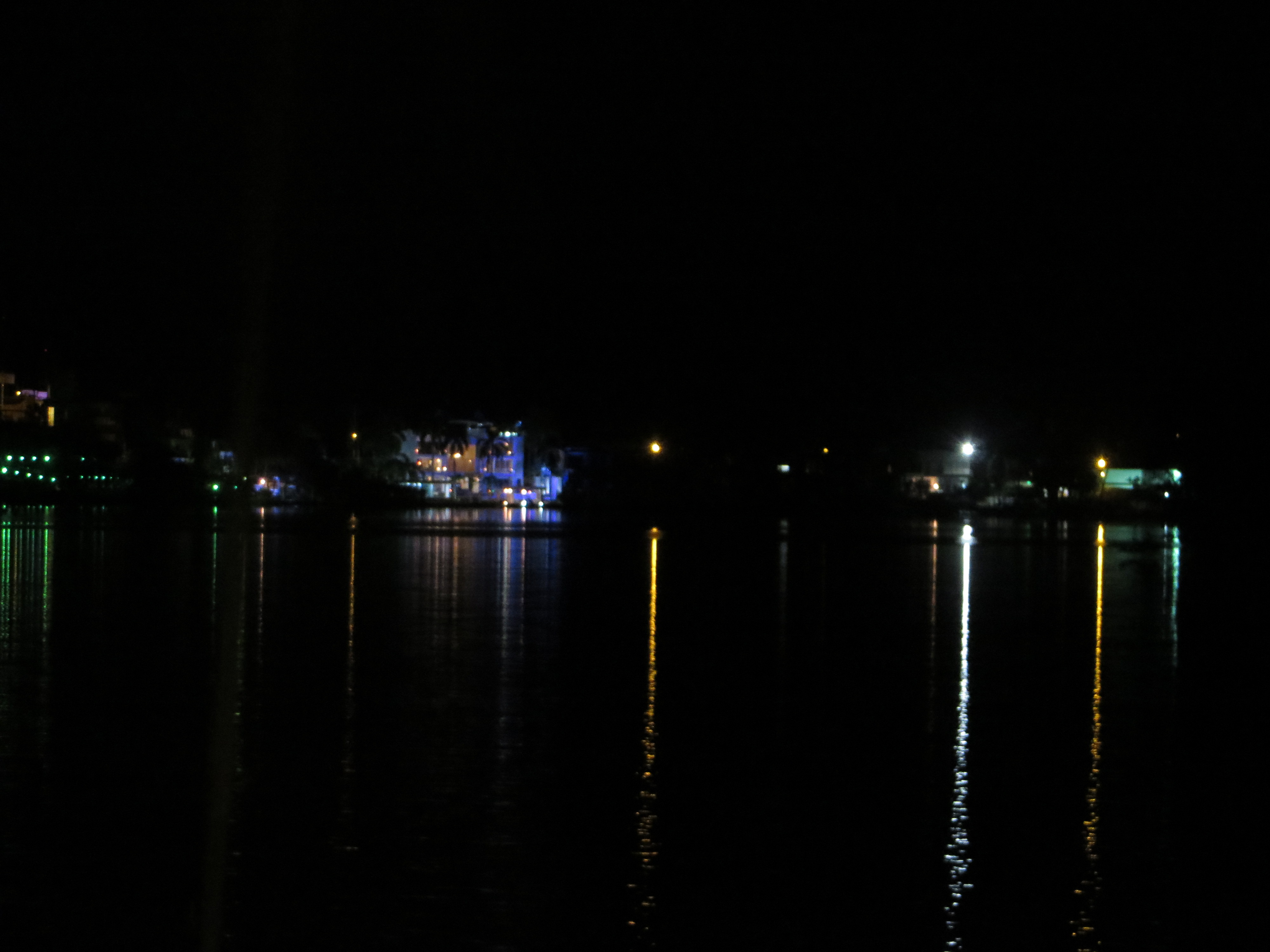Small distant lights and their reflections punctuate dark water.